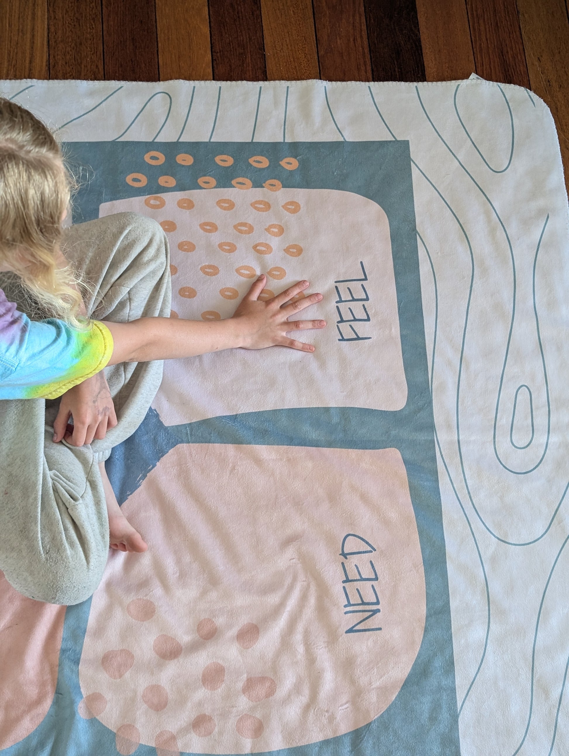 Child interacting with a communication blanket with the emotional regulation (see-think-feel-need) framework displayed. 